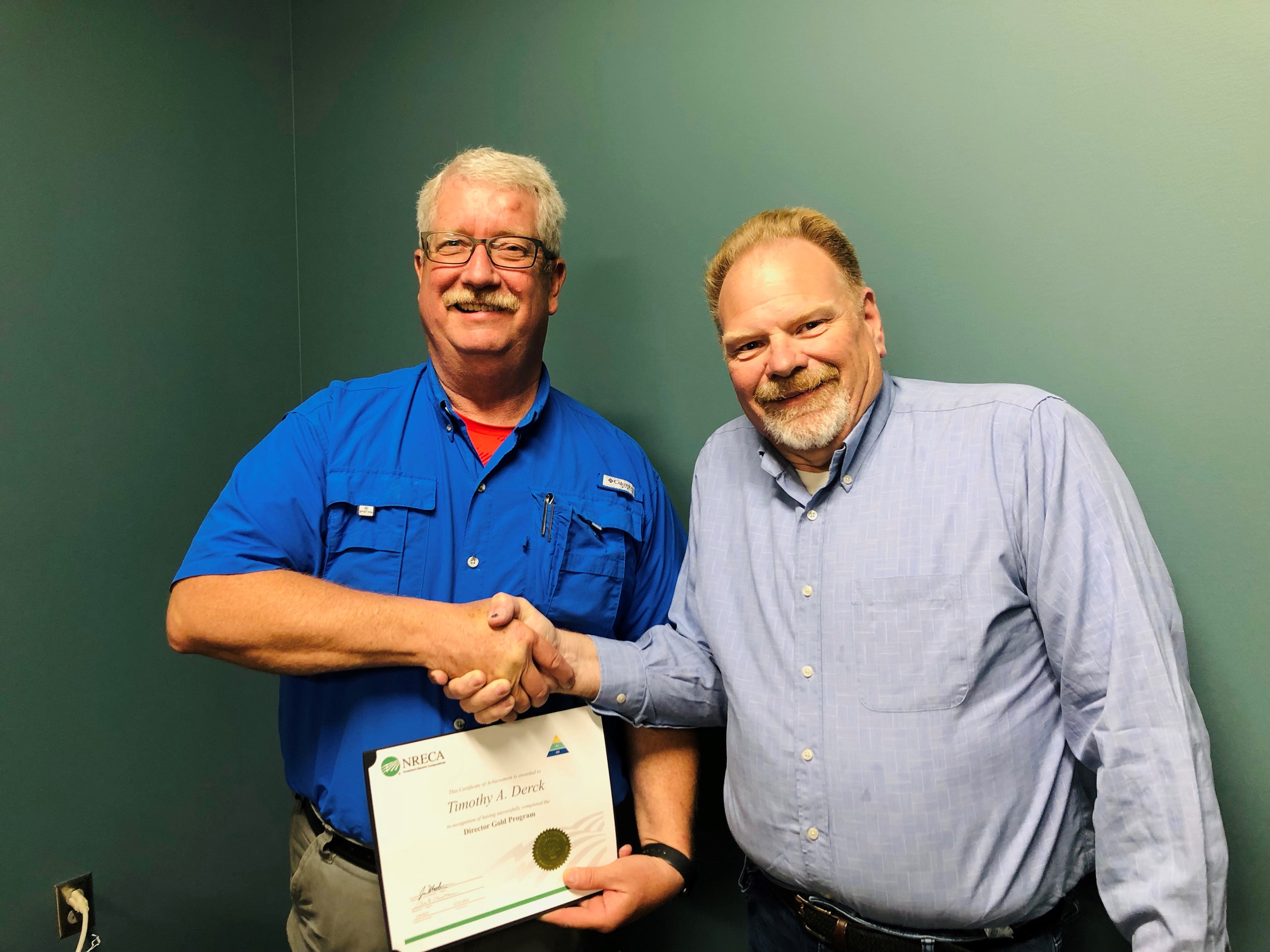 Trustee Tim Derck receives board director gold certificate from NRECA from board chariman Steve McMichael.
